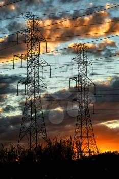 Group of high-voltage electricity power pylons during sunset in the countryside, Canada