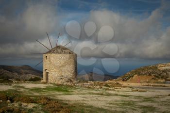 Beautiful view of a windmill on the top of a hill with a view on the ocean by a nice summer day in Naxos, Greece