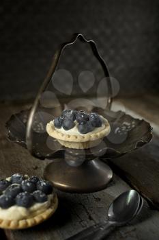 Top view of blueberry, strawberry and pistachios tartlets on a wooden table