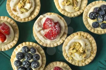 Blueberry, strawberry and pistachios tarts in a green tray 