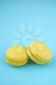 Two french traditional yellow macarons on pastel blue background