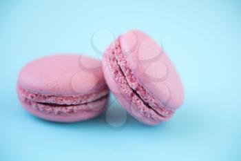 Two french traditional pink macarons on pastel blue background