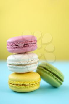 Pink, yellow, white and green traditional french macaroons on yellow and blue background