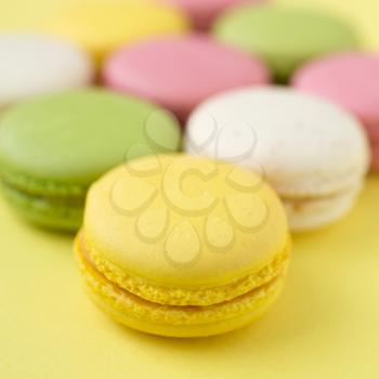 Pink, yellow, white and green traditional french macaroons on  yellow background