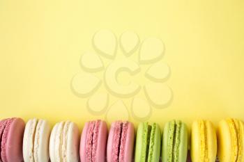 Row of traditional french colourful macarons on yellow background