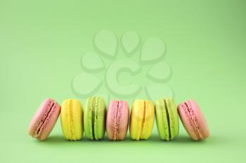 Row of traditional french macarons on green background
