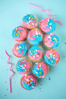 Top view of cupcakes with candles and  blue and pink icing on a blue background