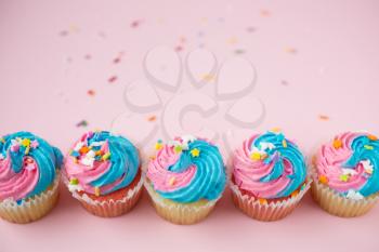 Top view of cupcakes with blue and pink icing on a pink background
