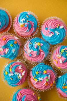 Top view of cupcakes with blue and pink icing on a yellow background