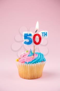 50th birthday cupcake with blue and pink icing on a pink background