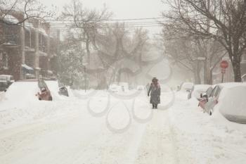 Anonyme woman walking in a street covered of snow during a heavy snowstorm in Montreal in Canada