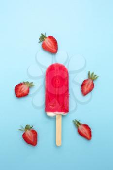 Strawberry popsicle with fresh strawberry on a blue background