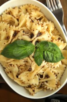 Bowl full of farfalle with dry tomato pesto and fresh basil on top
