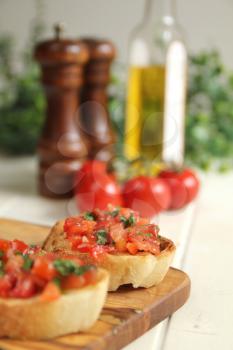 Close up of roasted brushetta with olive oil, garlic and fresh basil and fresh pepper in the background