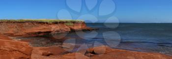 Red cliff in Cap aux Meules with waves in the ocean in the St-Lawrence golfe in iles de la madeleine in Canada