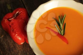 Carrot and grilled pepper soup on a wooden background