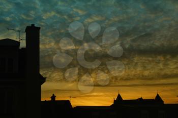 Blue and yellow sunset on a silhouette of a houses rooftop  in Europe